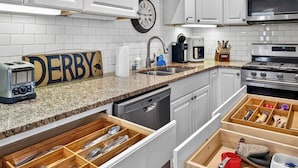 A kitchen with white cabinets, a granite countertop, a toaster, a coffee maker, and wooden drawers. - Spacious and cozy Highlands unit near attractions! (Louisville)