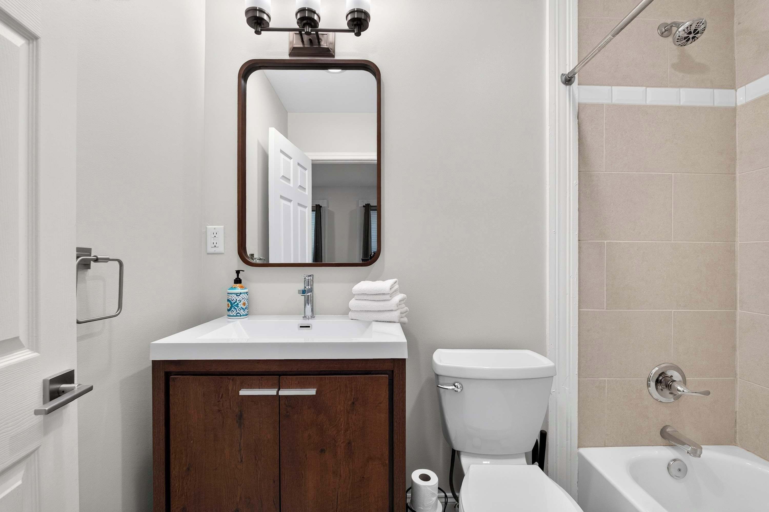 A bathroom with a white sink, a mirror, a toilet, and a shower area.