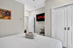 Ein Hotelzimmer mit einem Bett, einem an der Wand befestigten Fernseher, einer Tür und einem Sessel.
