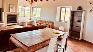 A kitchen with a wooden table, white chairs, a built-in oven, and a window overlooking greenery. - Villa with pool, Meia Praia beach, Lagos (Lagos)