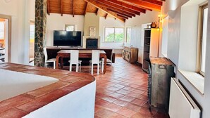 A spacious kitchen with a stone pillar, wooden ceiling beams, a TV, and a fireplace. - Villa with pool, Meia Praia beach, Lagos (Lagos)