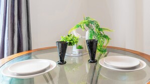 A round glass table with two white plates and two black glasses, accompanied by a small potted plant and a decorative item. - Central - Stay 4 - Paid Parking - Near Transport (Maidstone)