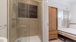 A bathroom with a glass-enclosed shower, a wooden wardrobe, and a bed with a white mattress. - Central - Stay 4 - Paid Parking - Near Transport (Maidstone)