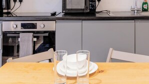 Una cocina con una mesa de madera, dos vasos transparentes y un plato blanco.