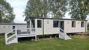 A mobile home with a porch, steps, and a small deck. - Static Caravan 2 Bed Sleeps 6 Overlooking Water (Northampton)