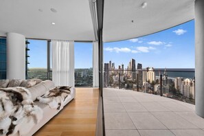 A modern bedroom with a large bed, a city view, and a balcony. - Signature Oceanview Residence | 2 Car Spaces (Broadbeach)