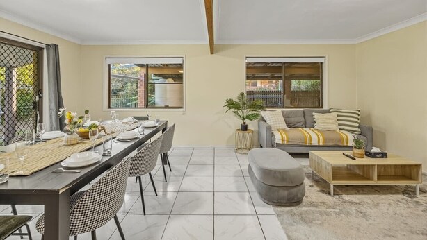 A dining area with a long table and chairs, a sofa, and a coffee table.