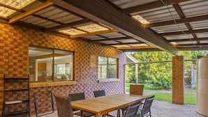 An outdoor patio with a brick wall, a wooden table, and chairs.