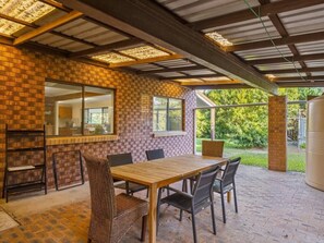 Une terrasse extérieure avec un mur en briques, une table en bois et des chaises.