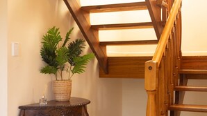 A wooden staircase with a glass ceiling, a small table with a plant, and a decorative item.