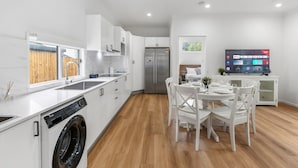 A modern kitchen with white cabinetry, a built-in dishwasher, and a stainless steel refrigerator.