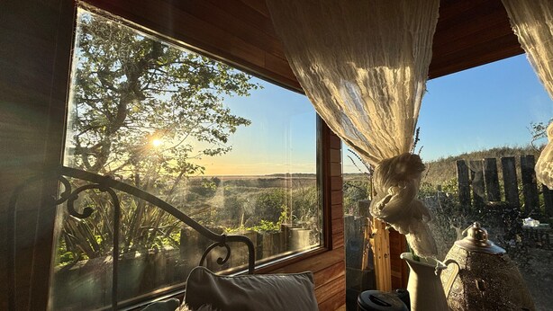 Une pièce avec une grande fenêtre, un lit, une lampe et un objet décoratif.