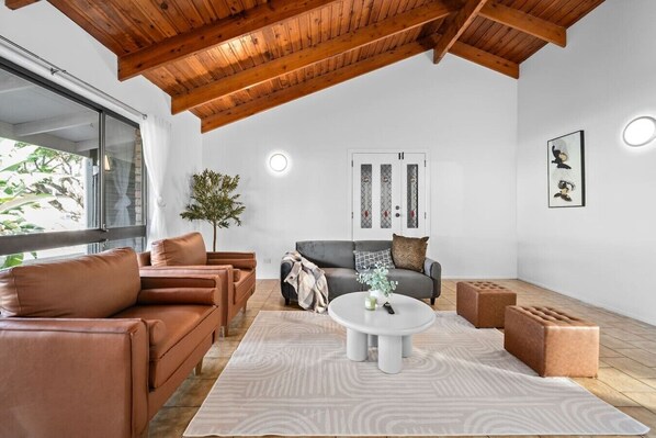 A spacious living area with leather sofas, a coffee table, and a wooden ceiling.