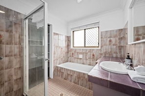 A modern bathroom with a glass shower enclosure, a freestanding bathtub, and a vanity with a sink.
