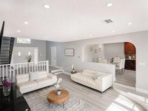 A modern living room with two sofas, a coffee table, and a staircase.