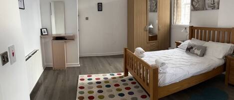 A bedroom with a bed, a wardrobe, a desk, a mirror, and a window.