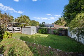 A backyard with a covered patio, a shed, a fenced area, and a vehicle. - Cozy Self-Contained |Hospital, Train & Shop Nearby (Loganlea)