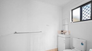 Une salle de bain avec des toilettes, un lavabo, un miroir et une fenêtre.