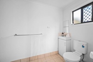 Un baño con inodoro, lavabo, espejo y ventana.