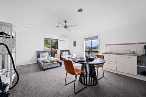 Una habitación moderna con dos camas, una mesa de comedor y una zona de cocina.