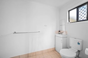 Ein kleines, sauberes Badezimmer mit Toilette, Waschbecken und Fenster.
