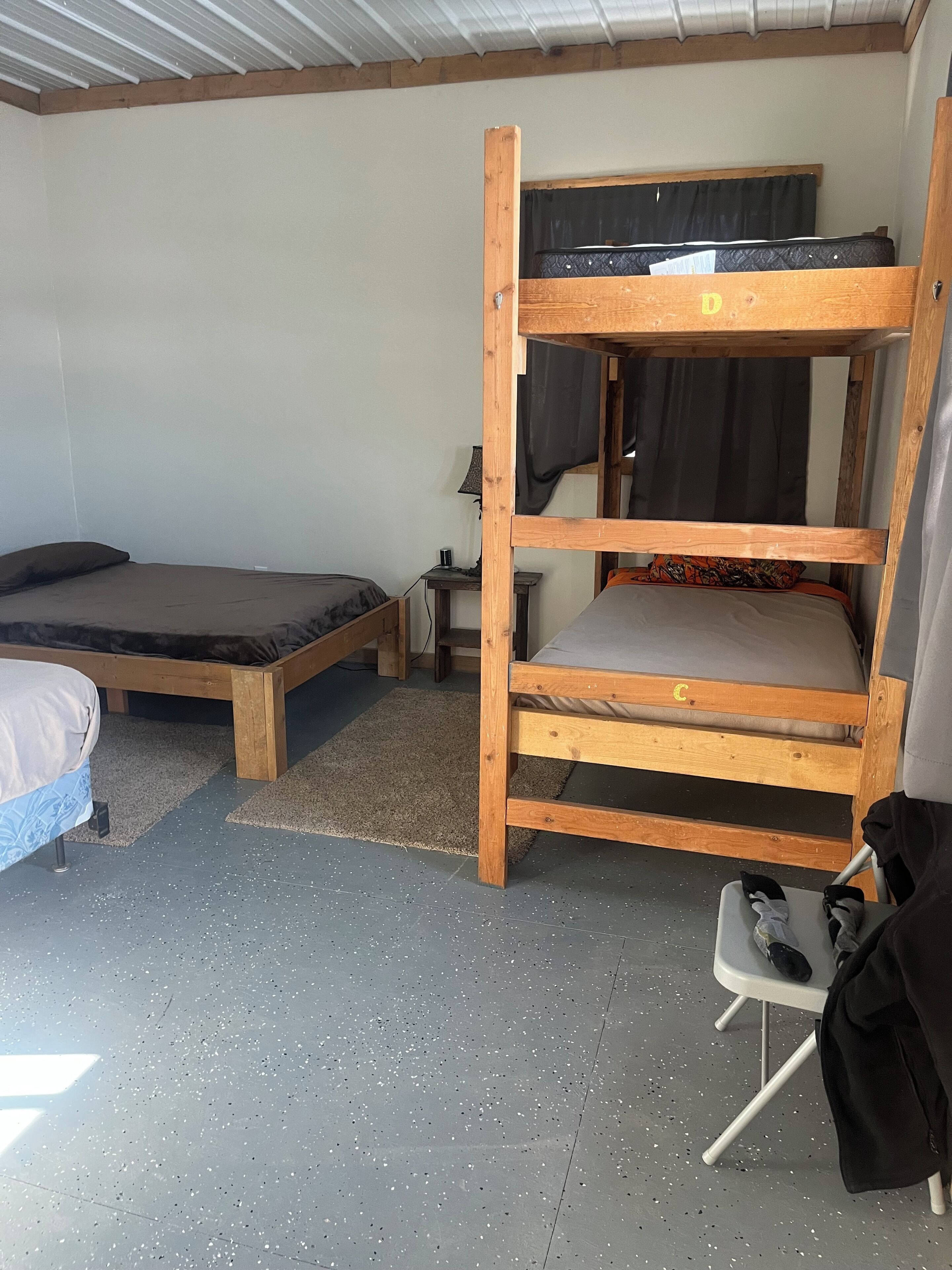 A bunk bed room with a desk, chair, and a small table with a lamp.