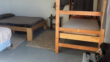 A bunk bed room with a desk, chair, and a small table with a lamp.