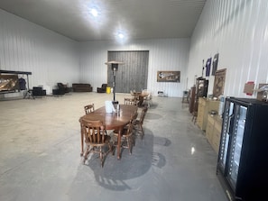 A spacious room with a large dining table, chairs, a sofa, and a cabinet.