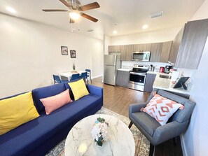 A modern living room with a sofa, coffee table, and a dining area with chairs. - Bright 1BR Retreat | Central Miami (Miami)