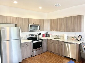 A modern kitchen with stainless steel appliances, wooden cabinets, a dishwasher, and a granite countertop. - Bright 1BR Retreat | Central Miami (Miami)
