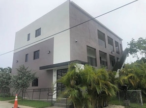 A modern two-story building with a flat roof, a balcony on the second floor, and a gated entrance. - Bright 1BR Retreat | Central Miami (Miami)