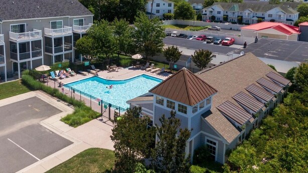 A residential building with a swimming pool, multiple balconies, and a parking area. - Rehoboth 4BR Townhome Sleeps 10 Bike to Beach (Rehoboth Beach)