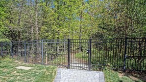 A paved pathway leading to a gated area with a metal fence, surrounded by greenery and trees. - Rehoboth 4BR Townhome Sleeps 10 Bike to Beach (Rehoboth Beach)