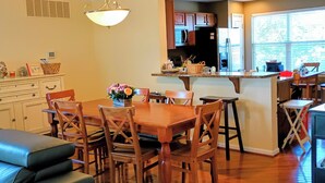 A dining area with a wooden table and chairs, a kitchen with dark cabinets, and a window with blinds. - Rehoboth 4BR Townhome Sleeps 10 Bike to Beach (Rehoboth Beach)