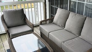 A wicker sofa with grey cushions and a glass-top table on a covered porch. - Rehoboth 4BR Townhome Sleeps 10 Bike to Beach (Rehoboth Beach)