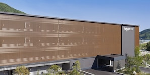 A modern building with a large corrugated metal facade, a flat roof, and a sign reading 'Rakuten STAY'.