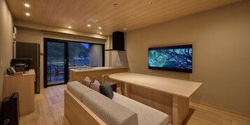 Una cocina moderna con horno empotrado, un comedor con banco y un televisor montado en la pared.