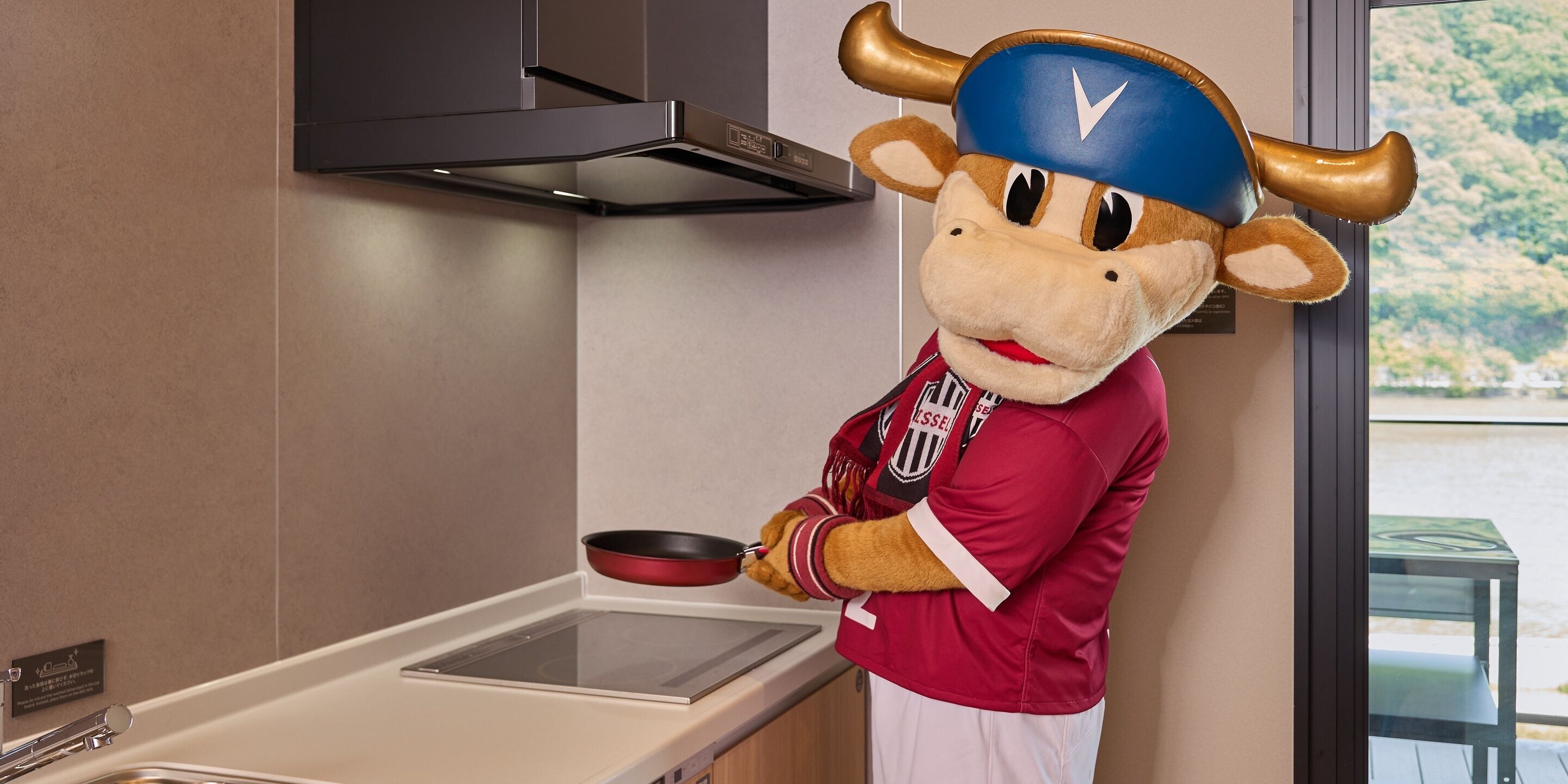 A mascot in a kitchen area with a stove, a sink, and a window with a view.
