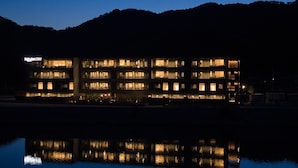 A multi-story hotel with illuminated windows, a reflection in the water, and a sign reading 'Rooftop Stay'.