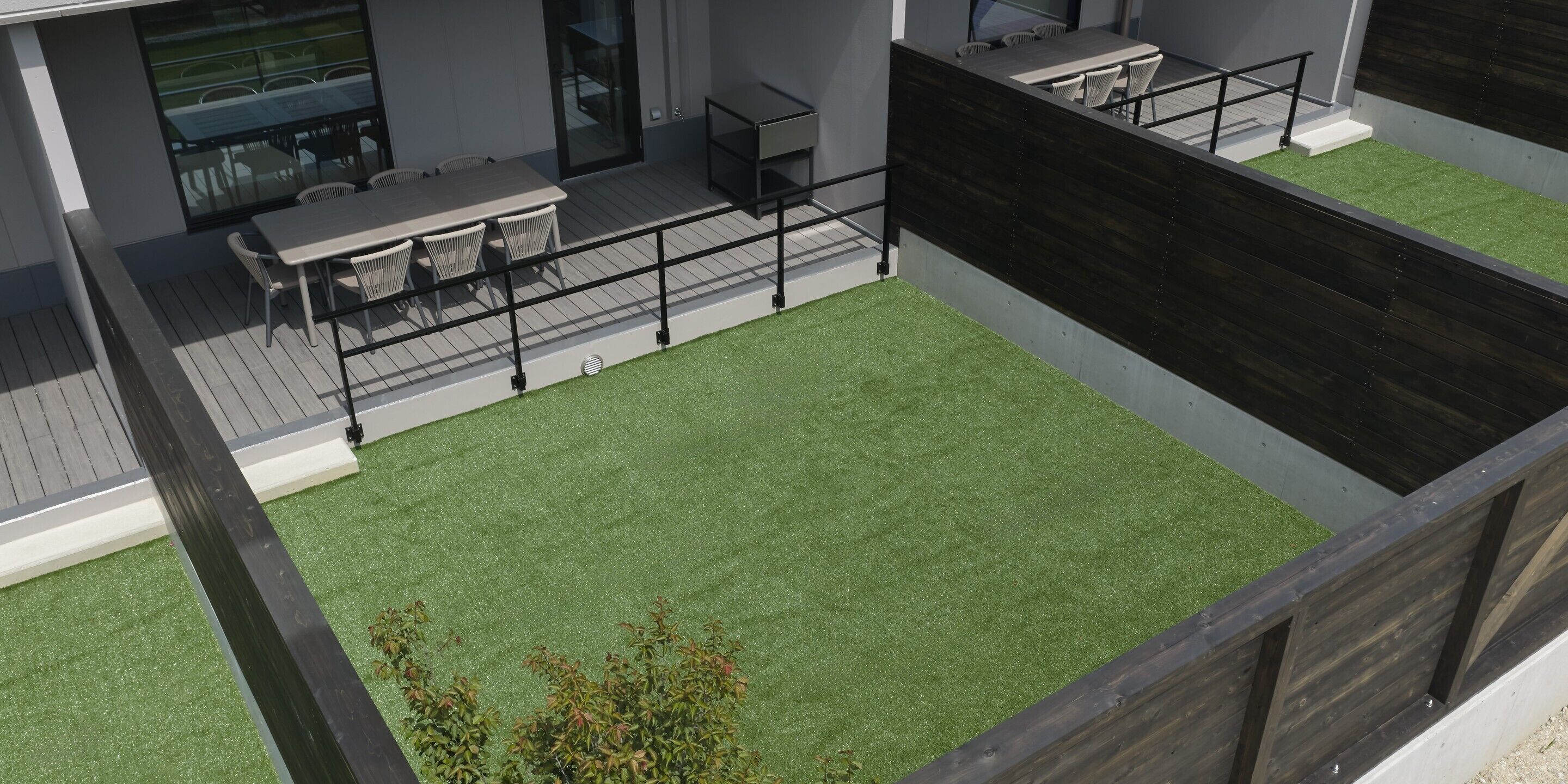 Una terrazza sul tetto con zona pranzo, prato sintetico e pavimento in legno.