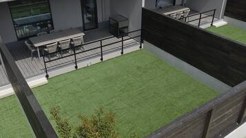 Una terrazza sul tetto con zona pranzo, prato sintetico e pavimento in legno.