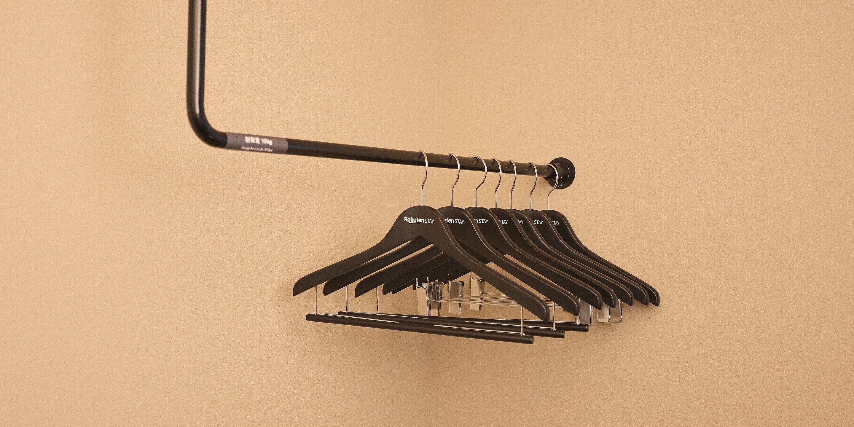 A wall-mounted clothing rack with multiple hangers against a plain wall.