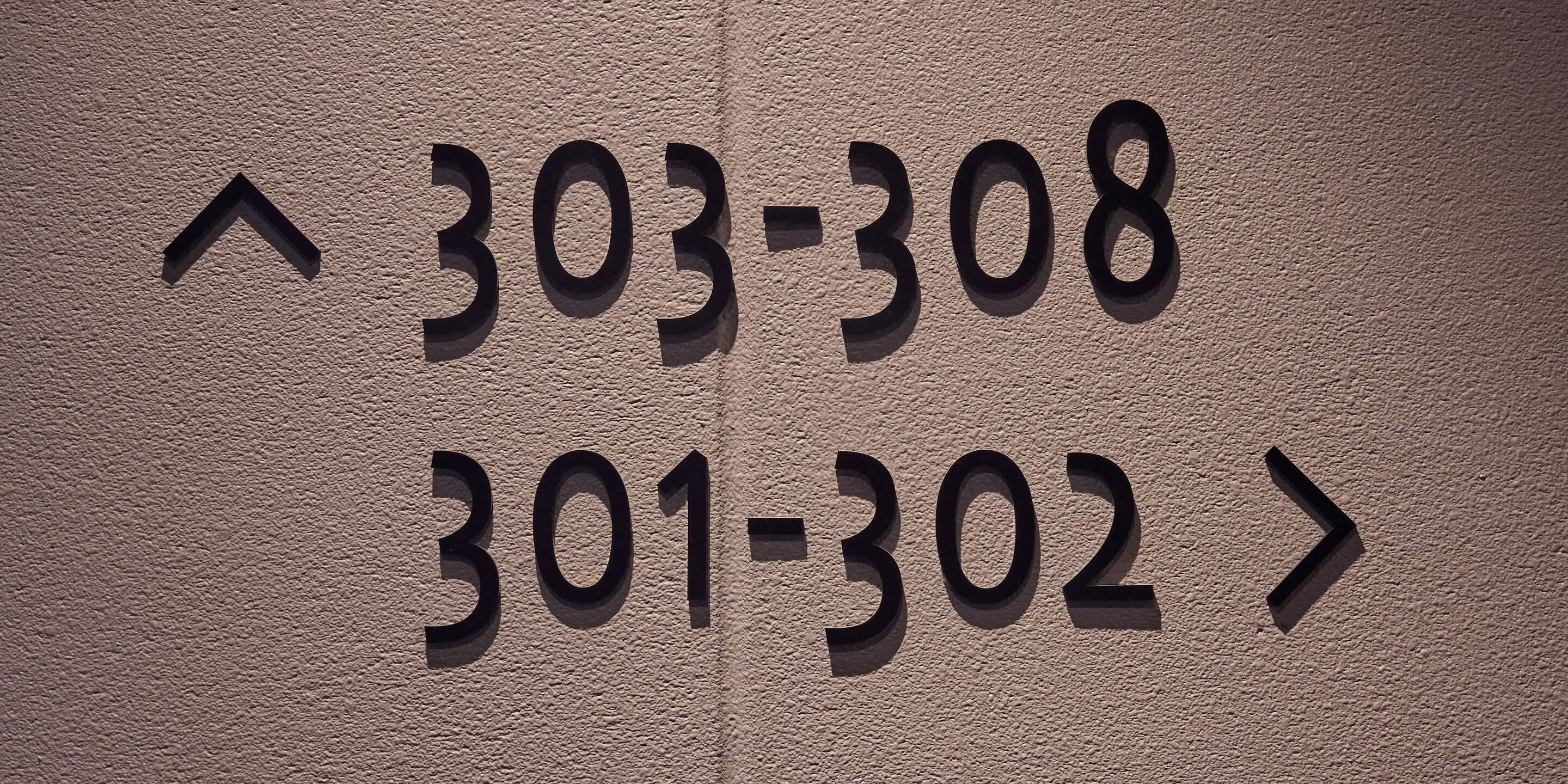 A wall with numbers '303-308' and '301-302' indicating room numbers.
