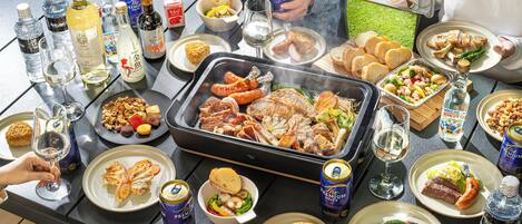 Una mesa con diversos alimentos, bebidas y una parrilla.