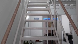 A white staircase with a handrail, leading to a landing with a sofa and a plant. - Luxury apartment close to the sea north of Cartagena (Cartagena de Indias)