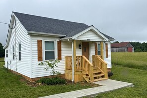 A single-story house with a front porch, a small front yard, and a barn in the background. - The Traveler's Cottage - 15 minutes to sports park, downtown and Bourbon Trail (Elizabethtown)