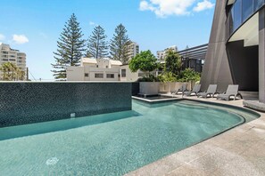 A swimming pool with clear water, surrounded by lounge chairs and a tiled deck. - 『CASSA VUE』- Cozy Living | Modern 3-BR (Broadbeach)