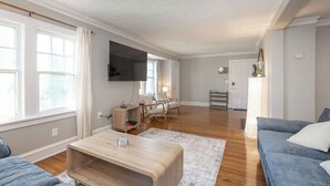 Een moderne woonkamer met een flatscreen televisie, een bank, een salontafel en een fauteuil.