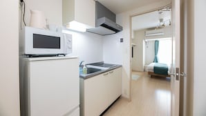 A compact kitchen with a microwave, stove, and cabinets. - Uni Brilliart Hakata (Fukuoka City)
