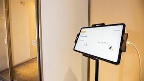 A tablet displaying a language selection screen, mounted on a wall in a hallway. - Uni Brilliart Hakata (Fukuoka City)